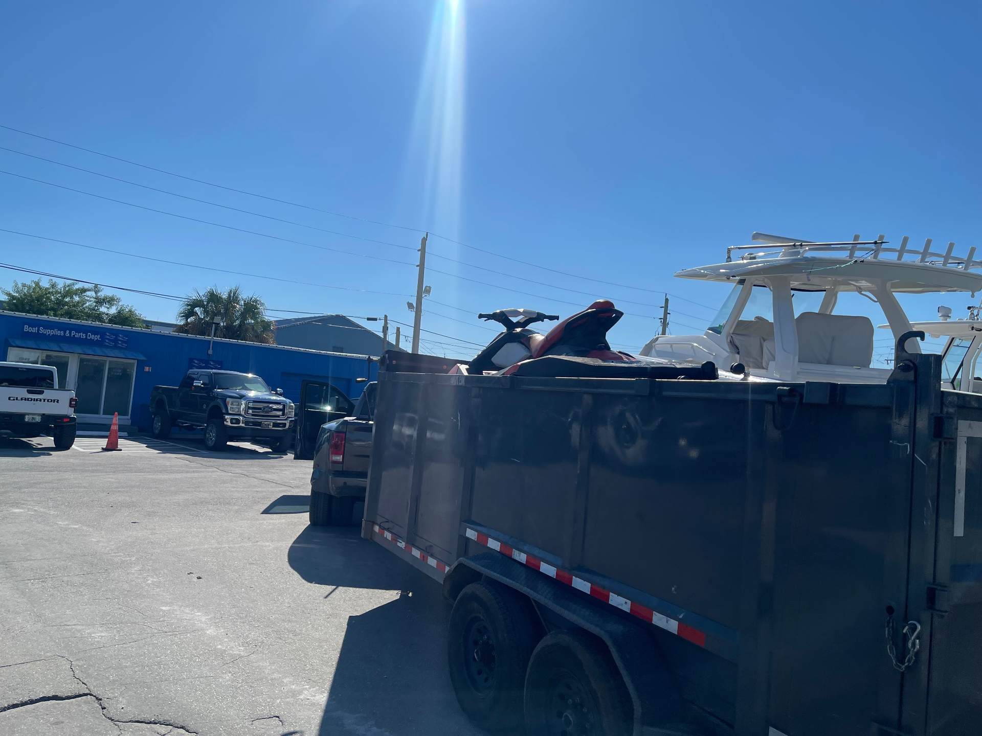 Red and black jet ski loaded on an All Out Rubbish dump trailer leaving the boat marina for disposal