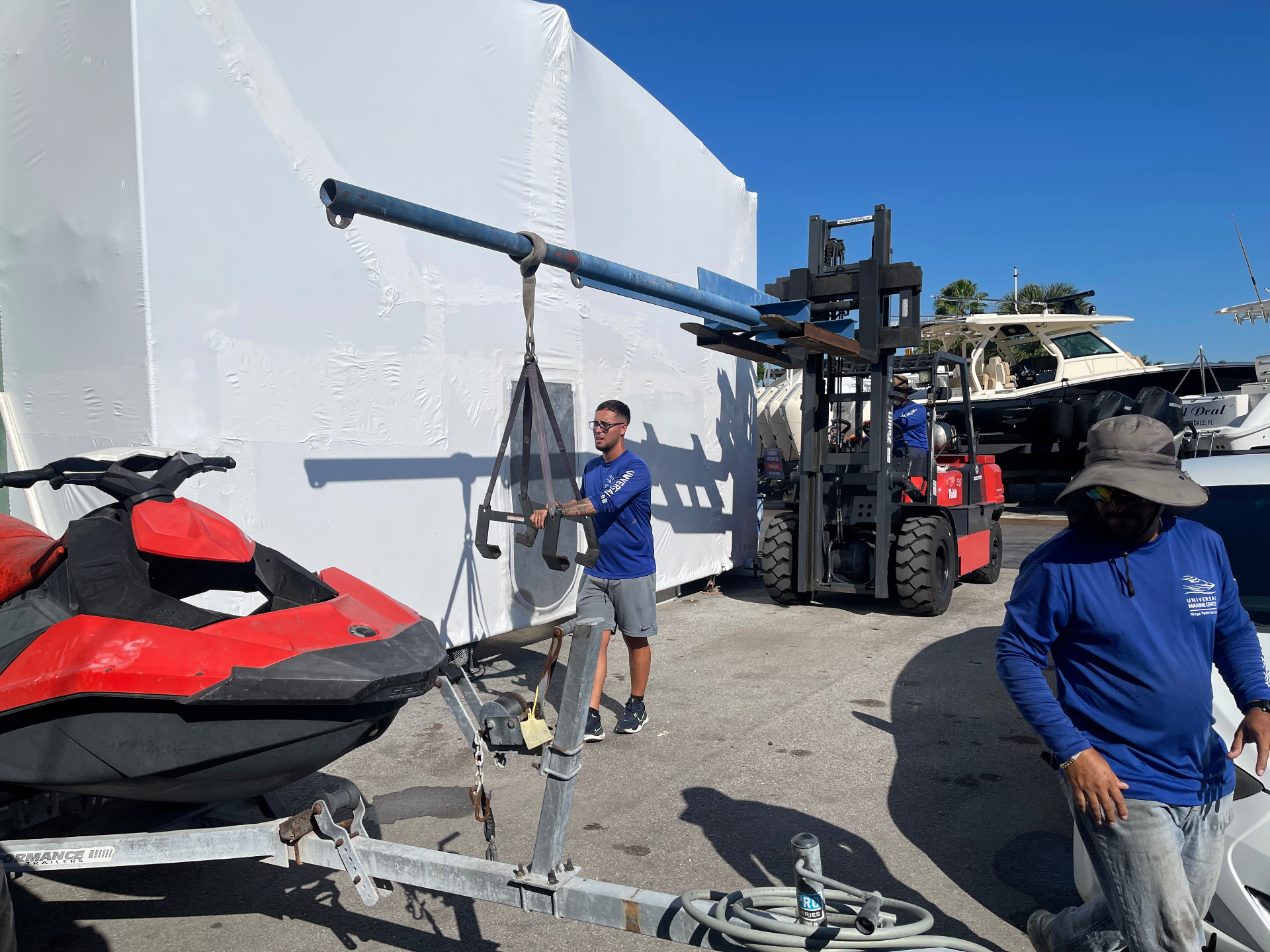 All Out Rubbish working with a marina forklift to lift a jet ski off its trailer for removal at a boat marina