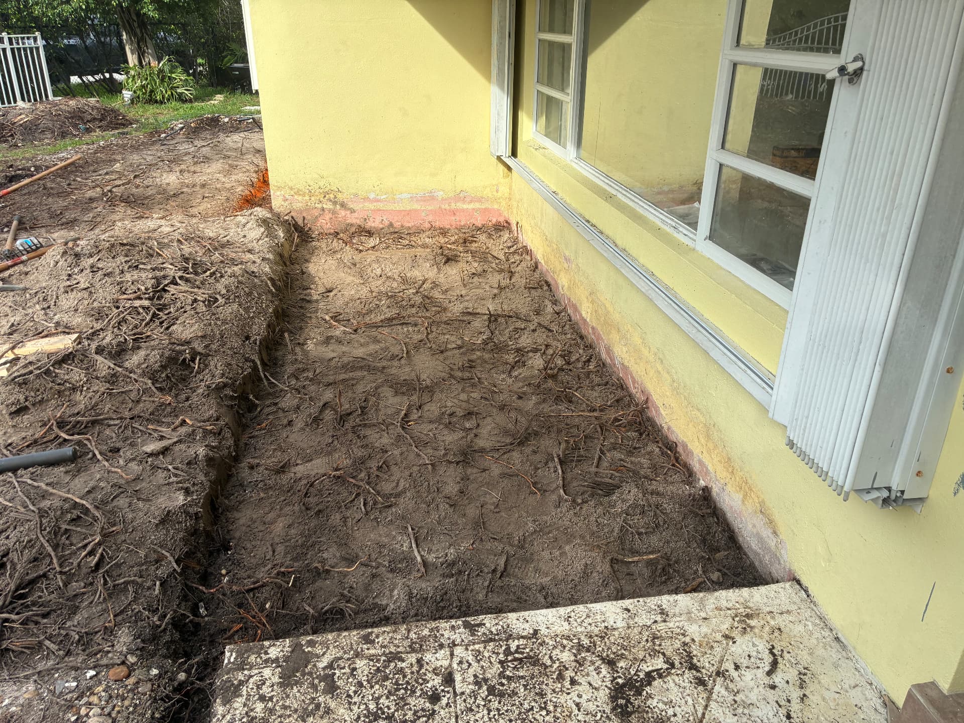 Corner view — trench graded, tools staged — land grading and concrete slab prep by All Out Rubbish in Palm Beach County, Florida